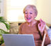 Join One of Our Virtual Groups Happy mature woman waving to someone while having a video call over laptop at home. Gray-haired senior woman waving hand in front of laptop while having video call with her family members.